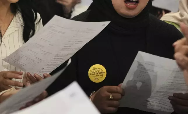 A participant wears a pin with a verse from "You'll Be In My Heart" by Phil Collins during a gathering of "Nyanyi Bareng Jakarta" or "Singing Together Jakarta" community in Jakarta, Indonesia, Saturday, July 19, 2025. (AP Photo/Dita Alangkara)