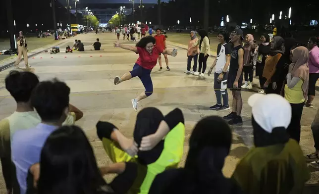 A participant jumps over a rubber rope during a community playing gathering in Jakarta, Indonesia, Friday, July 11, 2025. (AP Photo/Dita Alangkara)