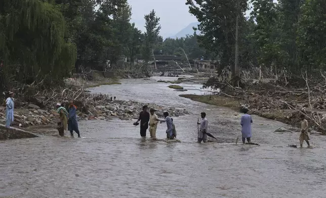 Local residents cross a stream following Friday's flash flooding hit area in Pishoreen village in Buner district, in Pakistan's northwest, Sunday, Aug. 17, 2025. (AP Photo/Muhammad Sajjad)