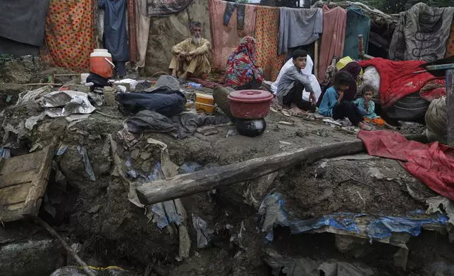 Villager Mateen Khan, second left, and his family members sit over the rubble of their damaged home following Friday's flash flooding at a neighbourhood of Pir Baba, an area of Buner district, in Pakistan's northwest, Sunday, Aug. 17, 2025. (AP Photo/Muhammad Sajjad)