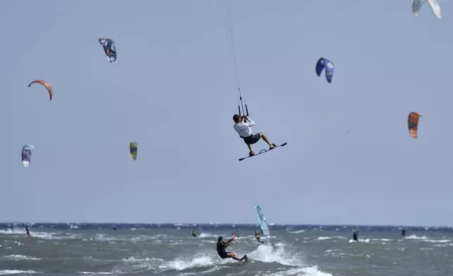A kiteboarder performs a jump during a windy day in Agios Nikolaos Artemida, east of Athens, Greece, Thursday, Aug. 7, 2025. (AP Photo/Thanassis Stavrakis)