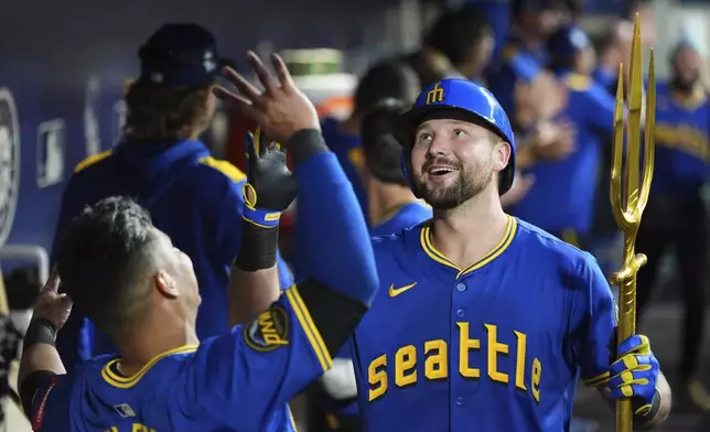 Seattle Mariners' Cal Raleigh celebrates his three-run home run against the Tampa Bay Rays with teammate Donovan Solano, left, during the eighth inning of a baseball game Friday, Aug. 8, 2025, in Seattle. (AP Photo/Lindsey Wasson)