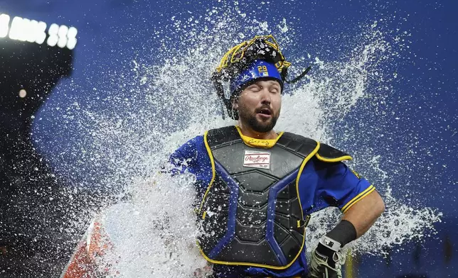 Seattle Mariners catcher Cal Raleigh reacts to being doused by teammate Victor Robles to celebrate his three-run home run after a win against the Tampa Bay Rays in a baseball game Friday, Aug. 8, 2025, in Seattle. (AP Photo/Lindsey Wasson)