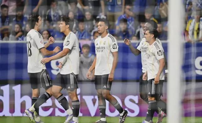 Real Madrid's Vinicius Junior, back right, is congratulated after scoring his side's 3rd goal during a Spanish La Liga soccer match between Real Oviedo and Real Madrid at Carlos Tartiere stadium in Oviedo, Spain, Sunday, Aug. 24, 2025. (AP Photo/Miguel Oses)