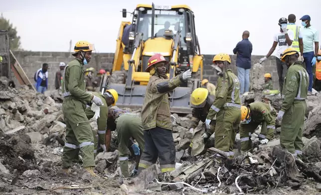 Firefighters search near the debris at the site of an airplane belonging to the African Medical and Research Foundation (AMREF) that crashed into a residential building in the Mwihoko area of Ruiru, in Kiambu County, Kenya, Wednesday, Aug. 7, 2024. (AP Photo/Patrick Ngugi)