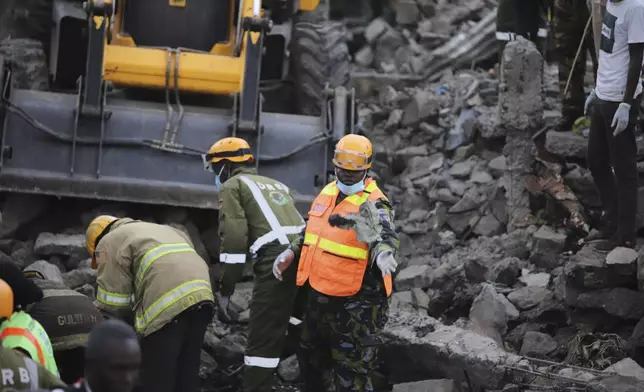 Firefighters search near the debris at the site of an airplane belonging to the African Medical and Research Foundation (AMREF) that crashed into a residential building in the Mwihoko area of Ruiru, in Kiambu County, Kenya, Wednesday, Aug. 7, 2024. (AP Photo/Patrick Ngugi)