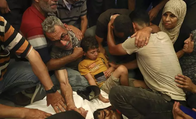 FILE - Ata Qasas, center left, mourns over the body of his son Rashad Qasas, who was killed while heading to an aid distribution hub, during his funeral in Rafah, southern Gaza Strip, Wednesday, June 11, 2025. (AP Photo/Mariam Dagga, File)