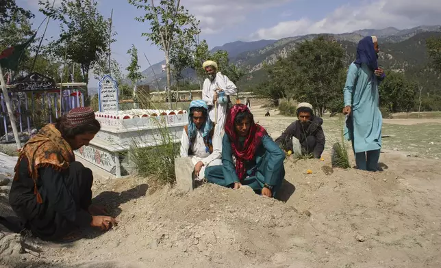 Relatives sit at the graves of three children allegedly killed in what Taliban authorities said was a Pakistani drone attack that killed eight civilians in Spera district of Khost province, Afghanistan, Thursday, Aug. 28, 2025. (AP Photo/Saifullah Zahir)