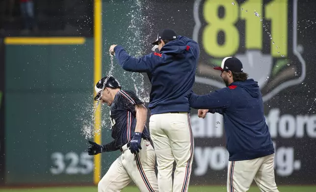 Cleveland Guardians' Kyle Manzardo, left, is doused by teammates after driving in the winning run against the Minnesota Twins at the end of the 10th inning of a baseball game, Friday, Aug. 1, 2025, in Cleveland. (AP Photo/Phil Long)