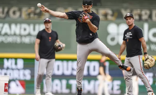 San Francisco Giants shortstop Willy Adames, center, warms up before a baseball game against the Milwaukee Brewers, Friday, Aug. 22, 2025, in Milwaukee. (AP Photo/Jeffrey Phelps)