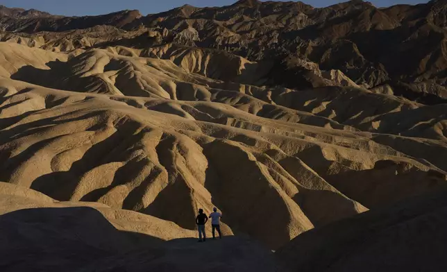 People look at the landscape at Zabriskie Point, Sunday, Aug. 3, 2025, in Death Valley National Park, Calif. (AP Photo/John Locher)