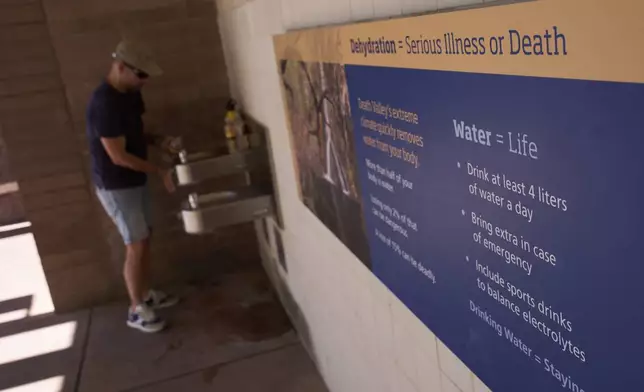 Pedro Luque, of Spain, fills up water bottles at the Furnace Creek Visitor Center, Sunday, Aug. 3, 2025, in Death Valley National Park, Calif. (AP Photo/John Locher)