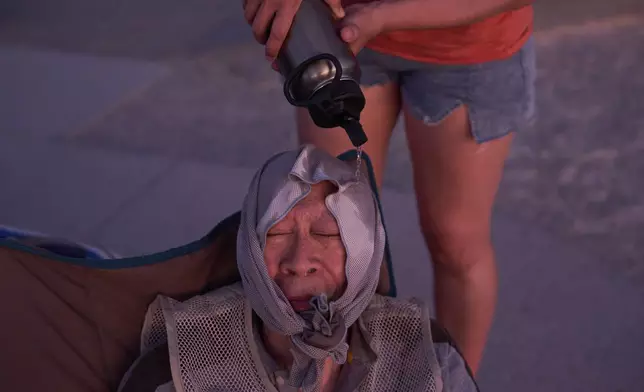 Grace Chyuwei pours water on Joe Chyuwei to help with the heat Sunday, Aug. 3, 2025, in Death Valley National Park, Calif. (AP Photo/John Locher)
