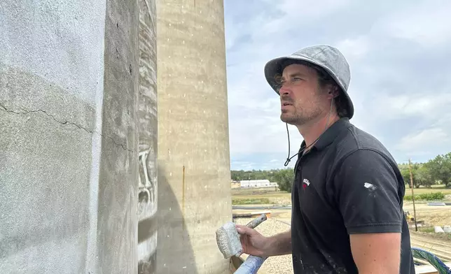 Artist Guido van Helten looks at the side of the silo where he is painting a mural on Monday, July 14, 2025, in Minot, N.D. (AP Photo/Jack Dura)
