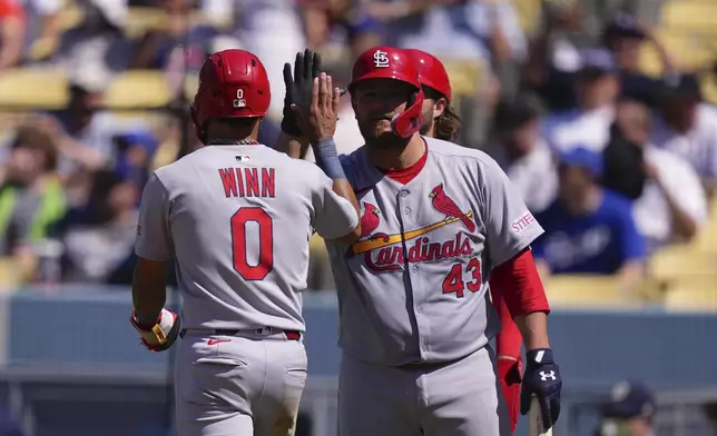 St. Louis Cardinals' Masyn Winn, left, is congratulated by Pedro Pages after scoring on a throwing error during the eighth inning of a baseball game Wednesday, Aug. 6, 2025, in Los Angeles. (AP Photo/Mark J. Terrill)