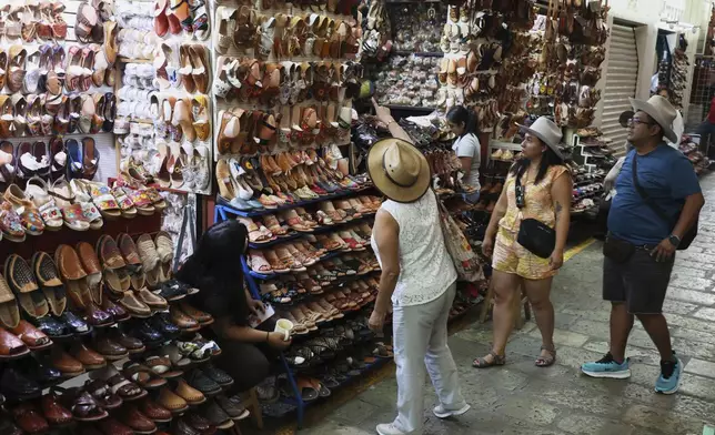 People look at a shop selling sandals known as "huaraches" at a market in Oaxaca, Mexico, Friday, Aug. 8, 2025. (AP Photo/Luis Alberto Cruz)