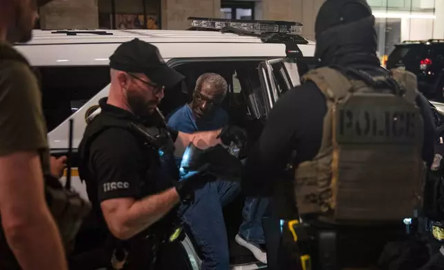 U.S. Secret Service agents, with the help of FBI agents, take a man into custody, center, near a homeless encampment in downtown Washington, Thursday, Aug. 14, 2025. (AP Photo/Cliff Owen)