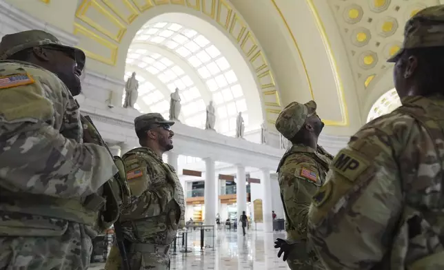 National Guard personnel look up and admire the valuted ceiling as they keep watch as travelers arrive at Union Station near the Capitol, in Washington, Friday, Aug. 15, 2025, in Washington. (AP Photo/Jacquelyn Martin)