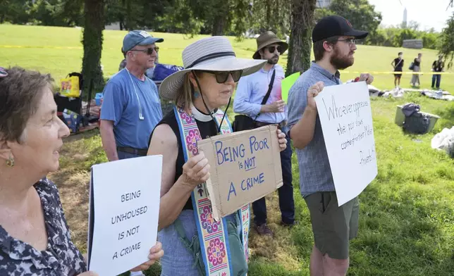 Protesters hold signs at a homeless encampment, Thursday, Aug. 14, 2025 in Washington. (AP Photo/Jacquelyn Martin)