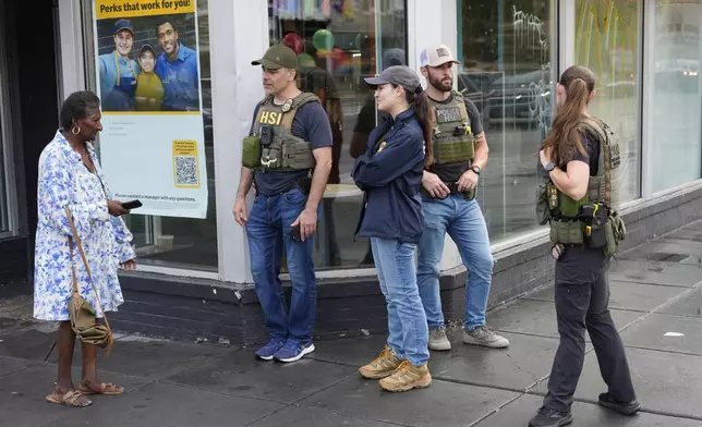 Department of Homeland Security Investigation officers stop to talk to a member of the community at the intersection of 14th and U Streets in northwest Washington, while on patrol Wednesday, Aug. 13, 2025. (AP Photo/Pablo Martinez Monsivais)
