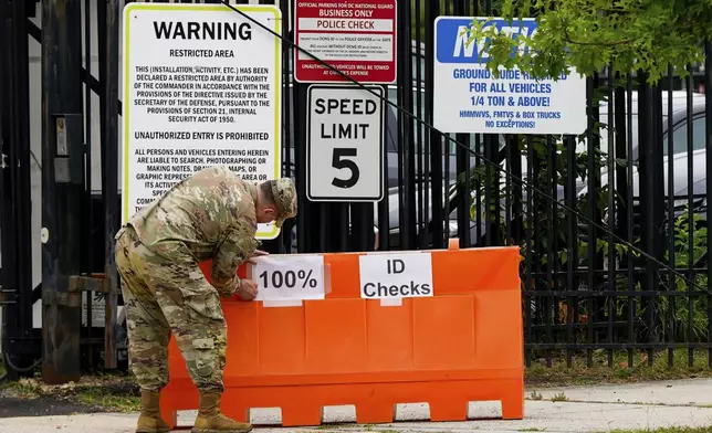 A member of the District of Columbia National Guard puts up signs for 100% ID checks outside the District of Columbia National Guard Headquarters, Tuesday, Aug. 12, 2025, in Washington. (AP Photo/Julia Demaree Nikhinson)
