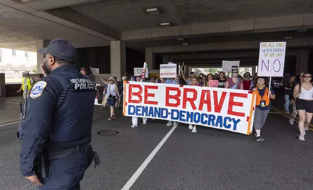 Activists with Free DC carry signs as they march to federal court, Friday, Aug. 15, 2025, in Washington. (AP Photo/Alex Brandon)