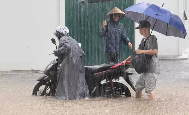People push a motorbike through floods from heavy rains in Hanoi, after Typhoon Kajiki passed through Vietnam, Tuesday, Aug. 26, 2025. (AP Photo/Hau Dinh)