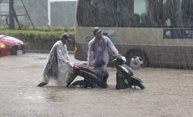 People push a motorbike through floods from heavy rains in Hanoi, after Typhoon Kajiki passed through Vietnam, Tuesday, Aug. 26, 2025. (AP Photo/Hau Dinh)