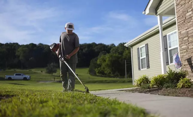 Michah Colley cuts the grass with a trimmer outside his home Wednesday, Aug. 27, 2025, in Talbott, Tenn. (AP Photo/George Walker IV)