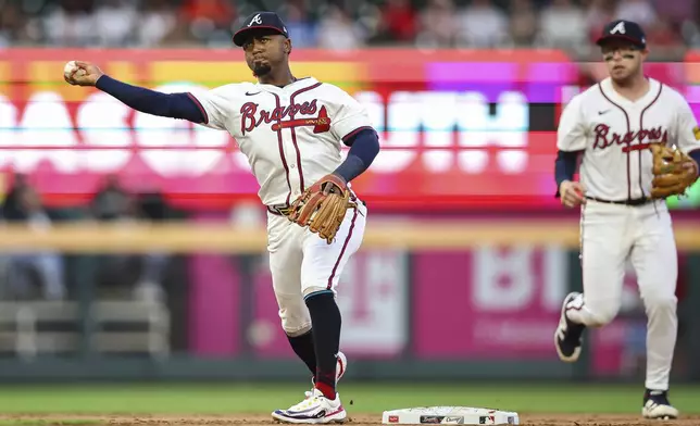 Atlanta Braves second baseman Ozzie Albies, left, throws to first base in the second inning of a baseball game against the Chicago White Sox, Monday, Aug. 18, 2025, in Atlanta. (AP Photo/Colin Hubbard)