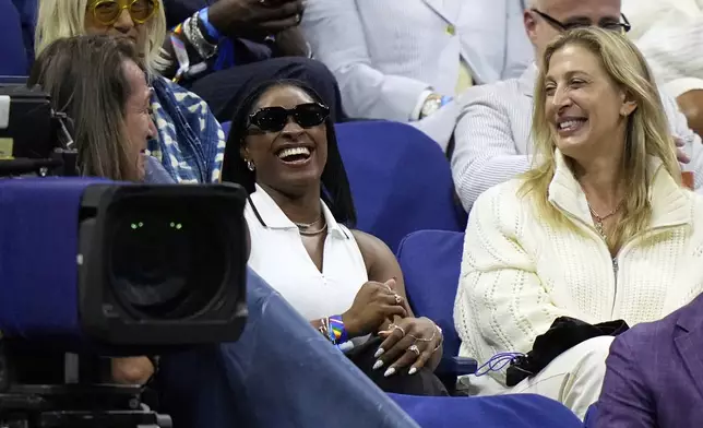 Gymnast Simone Biles, center, reacts after Coco Gauff, of the United States, mentioned her following Gauff's match against Donna Vekic, of Croatia, during the second round of the U.S. Open tennis championships, Thursday, Aug. 28, 2025, in New York. (AP Photo/Frank Franklin II)