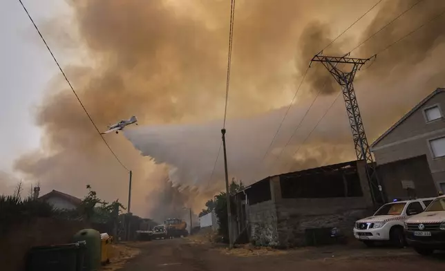 A firefighting plane drops water over a wildfire in Veiga das Meas, northwestern Spain, on Saturday, Aug. 16, 2025. (AP Photo/Lalo R. Villar)
