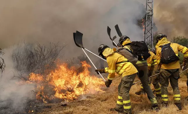 Firefighters battle a wildfire in Veiga das Meas, northwestern Spain, Saturday, Aug. 16, 2025. (AP Photo/Lalo R. Villar)