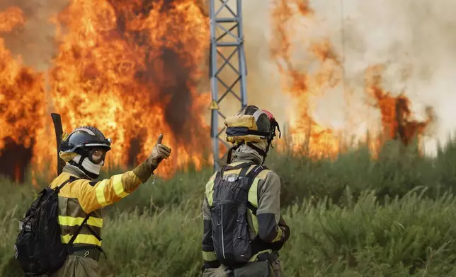 Firefighters battle a wildfire in Veiga das Meas, northwestern Spain, Saturday, Aug. 16, 2025. (AP Photo/Lalo R. Villar)