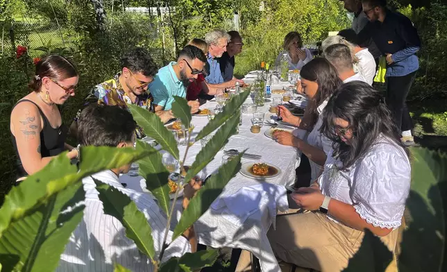 Visitors attend a joint meal at Martin Roetzel's 'The Monk Garden' in Berlin, Germany, Sunday, Aug. 17, 2025. (AP Photo/Fanny Brodersen)
