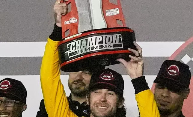 Ryan Blaney holds the championship trophy as he celebrates in Victory Lane after winning a NASCAR Cup Series auto race at Daytona International Speedway, Saturday, Aug. 23, 2025, in Daytona Beach, Fla. (AP Photo/John Raoux)