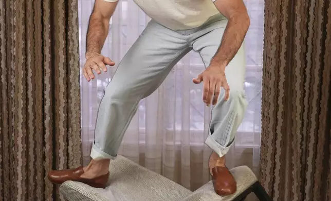 Michael Covino balances on a chart as he poses for a portrait to promote the comedy "Splitsville" on Thursday, Aug. 14, 2025, in Los Angeles. (AP Photo/Chris Pizzello)
