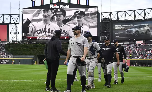 New York Yankees pitcher Carlos Rodón, center, walks to the dugout after warming up before a baseball game against the Chicago White Sox, Friday, Aug. 29, 2025, in Chicago. (AP Photo/Matt Marton)