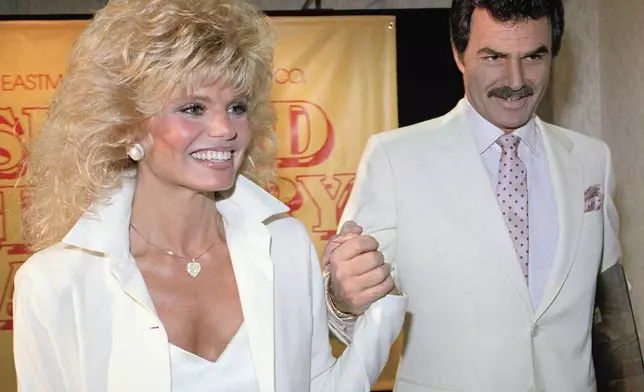 FILE - Burt Reynolds, right, holds hands with Loni Anderson at a luncheon, March 27, 1987, in Los Angeles. (AP Photo/Bob Galbraith, File)