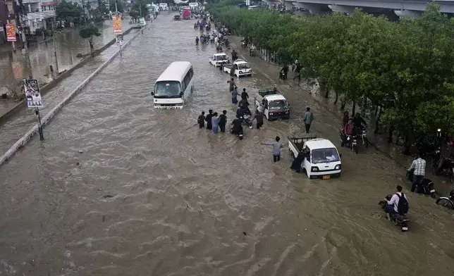 Drivers push their vehicles through a flooded road after heavy rainfall in Karachi, Pakistan, Tuesday, Aug. 19, 2025. (AP Photo/Fareed Khan)
