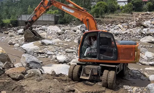 A worker with excavator clear an area filled with rocks after Friday's flash flood hit the area of Qadar Nagar in Buner district, in Pakistan's northwest, Monday, Aug. 18, 2025. (AP Photo/Mohammad Arif)