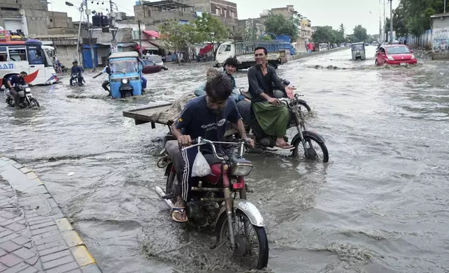 Motorcyclists navigate through a flooded road after heavy rainfall in Karachi, Pakistan, Tuesday, Aug. 19, 2025. (AP Photo/Fareed Khan)