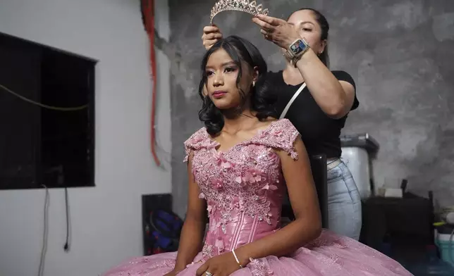 A stylist prepares Isela Santiago Morales for her 15th birthday party, organized by the community after her father's social media appeal drew support following her first sparsely attended celebration, in Axtla de Terrazas, Mexico, Saturday, Aug. 23, 2025. (AP Photo/Mauricio Palos)