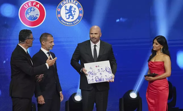Chelsea's President Jason Gannon, centre, holds the award for winning every UEFA club competition trophy during the Champions League soccer league phase draw in Monaco, Thursday, Aug. 28, 2025. (AP Photo/Laurent Cipriani)