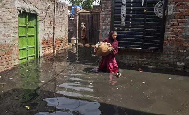 Residents retrieve belongings from their flooded home due to rising water level in Ravi River after torrential rains at a low-lying area on the outskirts of Lahore, Pakistan, Aug. 28, 2025. (AP Photo/K.M. Chaudary)