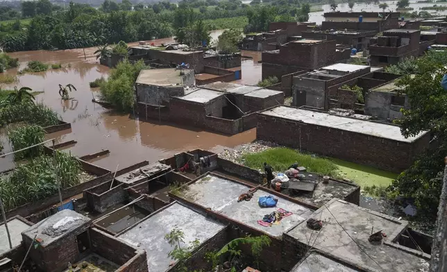 A resident retrieves belongings from his flooded home due to rising water level in Ravi River after torrential rains at a low-lying area on the outskirts of Lahore, Pakistan, Aug. 28, 2025. (AP Photo/K.M. Chaudary)