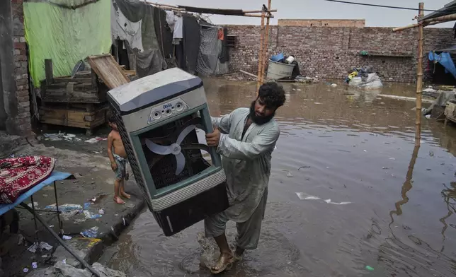 A resident retrieves a room cooler and other belongings from his flooded home due to rising water level in Ravi River after torrential rains at a low-lying area on the outskirts of Lahore, Pakistan, Aug. 28, 2025. (AP Photo/K.M. Chaudary)