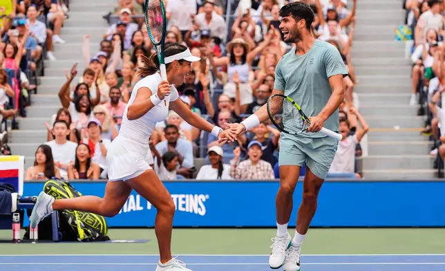 Carlos Alcaraz, right, of Spain, and Emma Raducanu, left, of Great Britain, celebrate during their mixed doubles match at the U.S. Open tennis championships, Tuesday, Aug. 19, 2025, in New York. (AP Photo/Yuki Iwamura)
