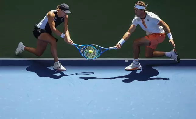 Casper Ruud, of Norway, left, plays a shot as partner Iga Swiatek, left, of Poland, covers during their mixed doubles match at the U.S. Open tennis championships, Tuesday, Aug. 19, 2025, in New York. (AP Photo/Yuki Iwamura)