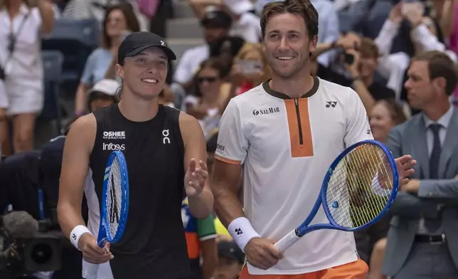 Iga Swiatek, left, of Poland, and Casper Ruud, right, of Norway, wave at fans after their mixed doubles match at the U.S. Open tennis championships, Tuesday, Aug. 19, 2025, in New York. (AP Photo/Yuki Iwamura)